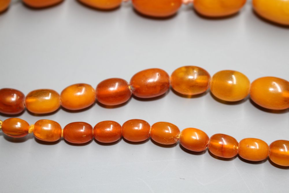 Two single strand graduated oval amber bead necklaces, with yellow metal clasps, one stamped 375,